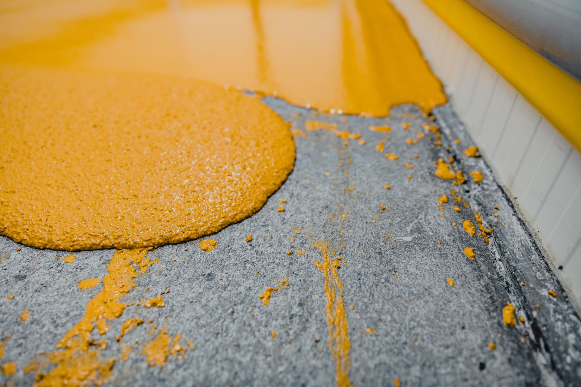 Un liquide jaune recouvre le sol en béton et déborde sur le côté, près d'un mur.