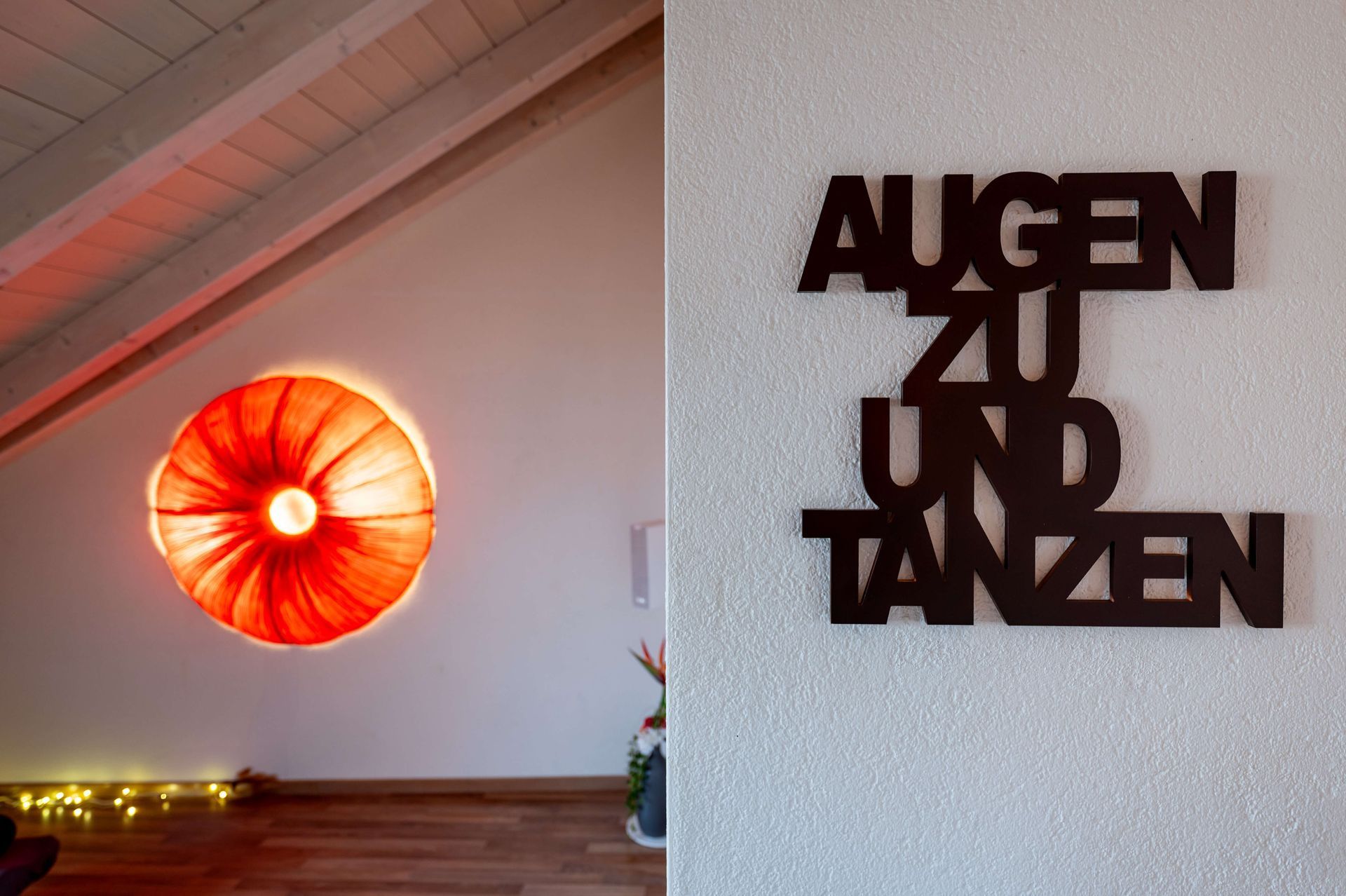 Blick in ein gemütliches Dachzimmer auf einen Schriftzug an der Wand mit den Worten Augen zu und Tanzen
