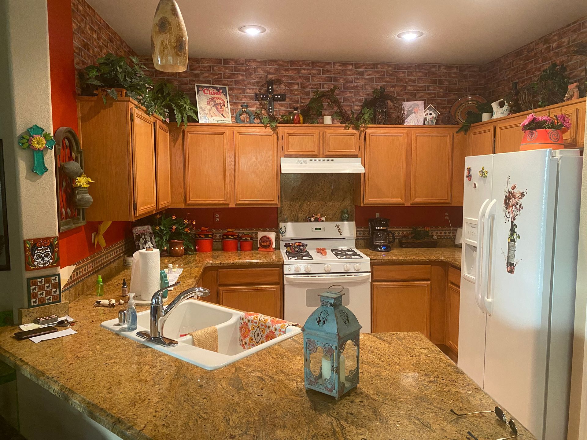 A kitchen with a sink , stove , refrigerator and a lantern on the counter.