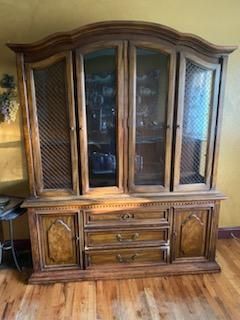 A wooden hutch with glass doors and drawers in a living room.