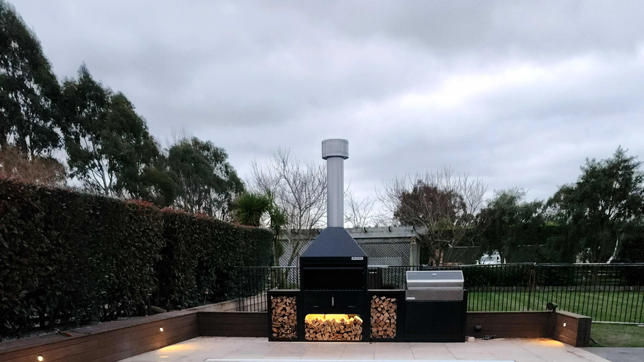 A large outdoor grill with a chimney on top of it.