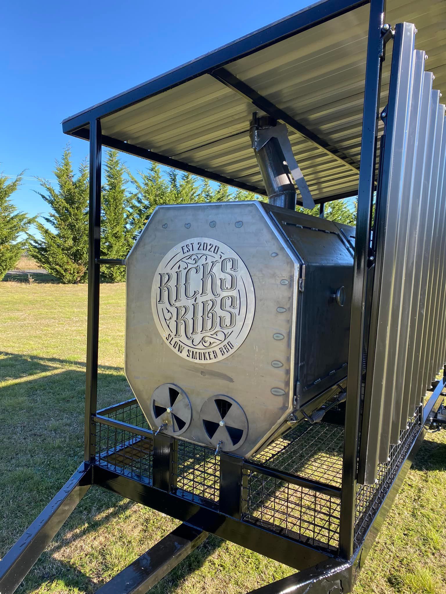 A large metal object is sitting on top of a commercial trailer smoker by SmokeDogg