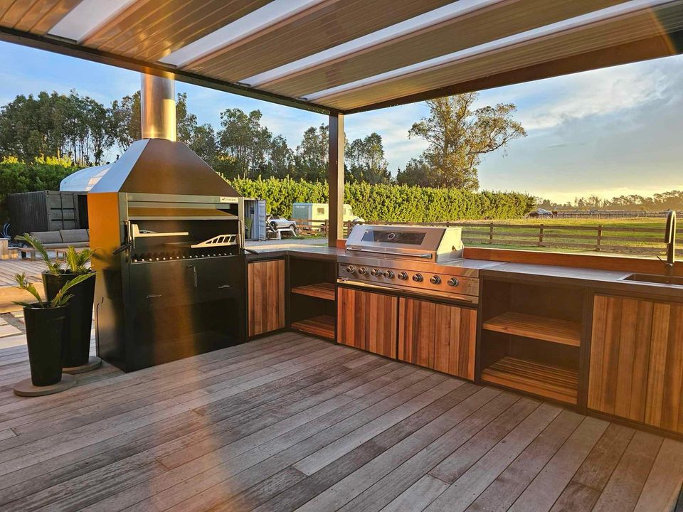 An outdoor kitchen with wooden cabinets and stainless steel appliances