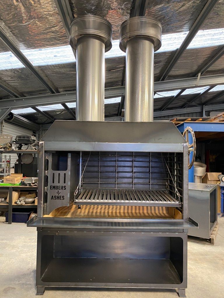 A large stainless steel grill is sitting in a warehouse.