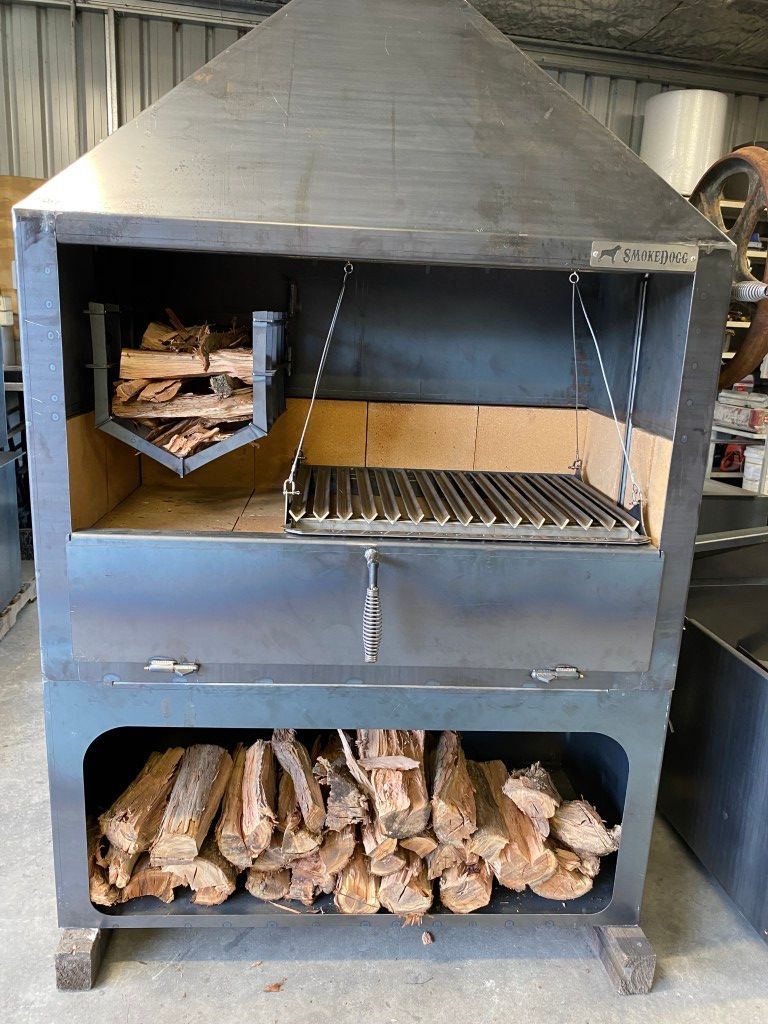 A large metal grill with a lot of wood in it.