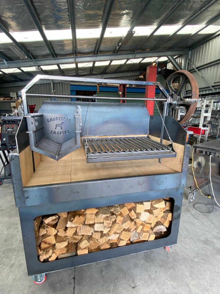 A large metal grill is sitting in a warehouse next to a pile of wood.