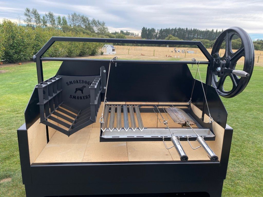 A large black grill is sitting on top of a lush green field.