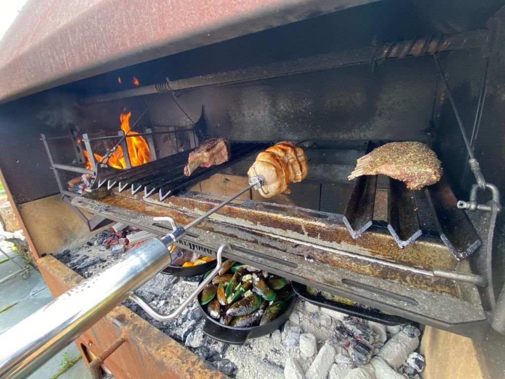 A grill with meat and vegetables cooking on it.