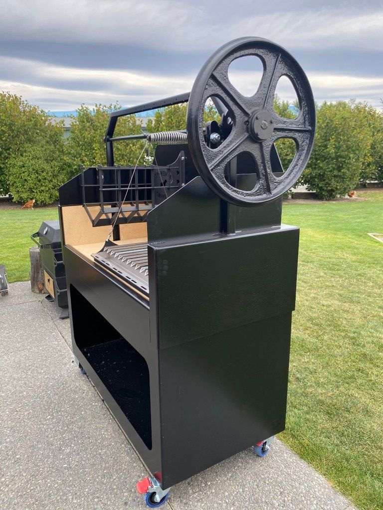 A large black machine with wheels is sitting on top of a concrete surface.