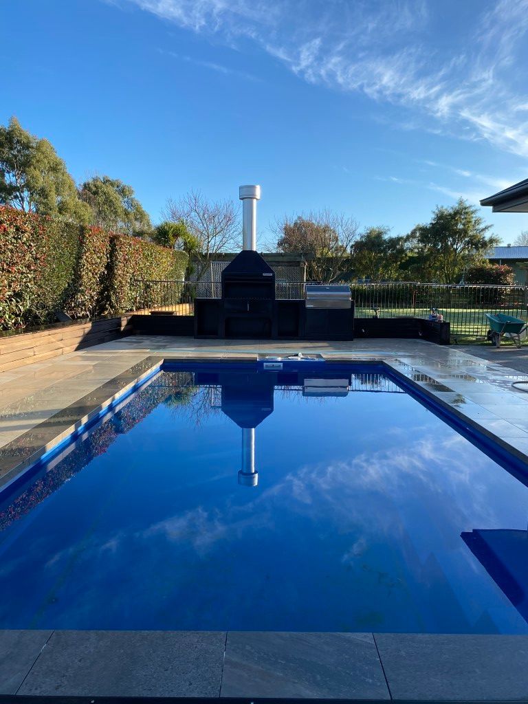 A large swimming pool with a grill in the background.