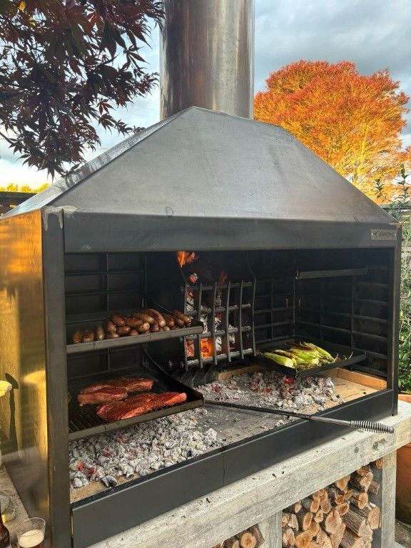A large grill with a hood is cooking food on it.