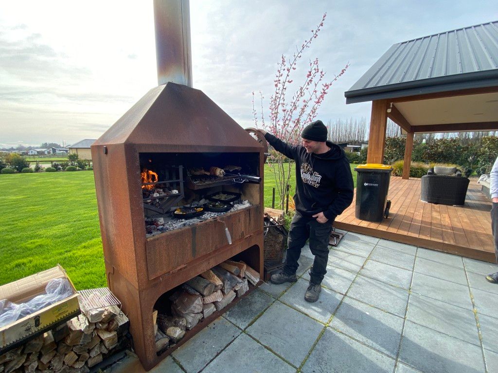 A man is standing in front of a barbecue grill.