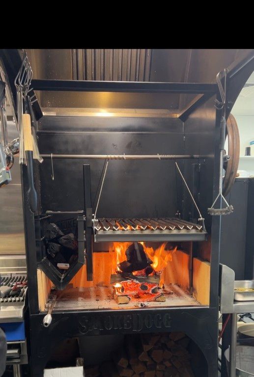 A large grill is cooking food in a kitchen.