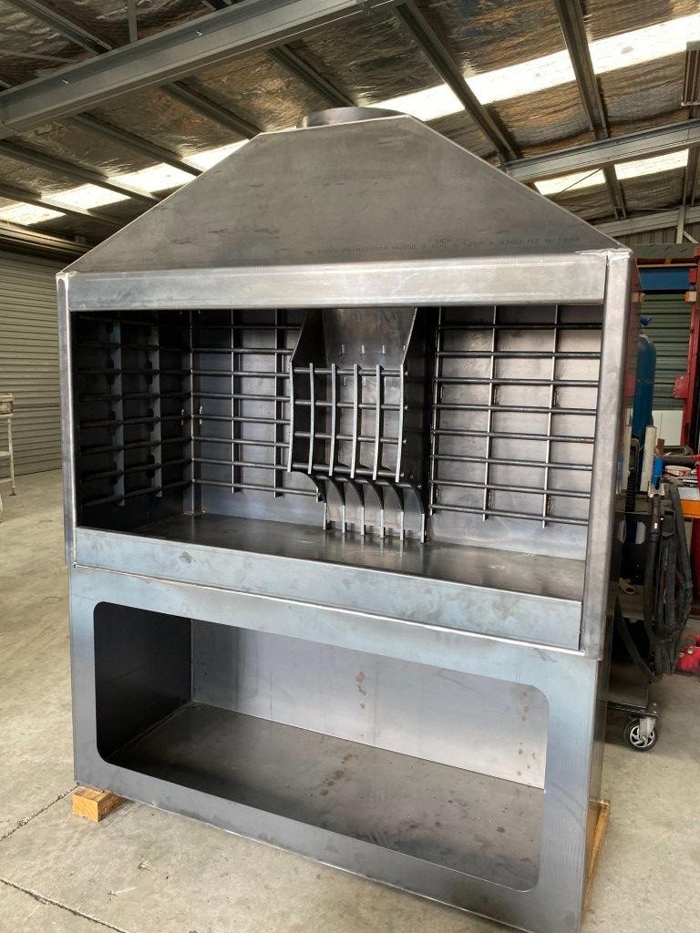 A large stainless steel grill is sitting in a warehouse.