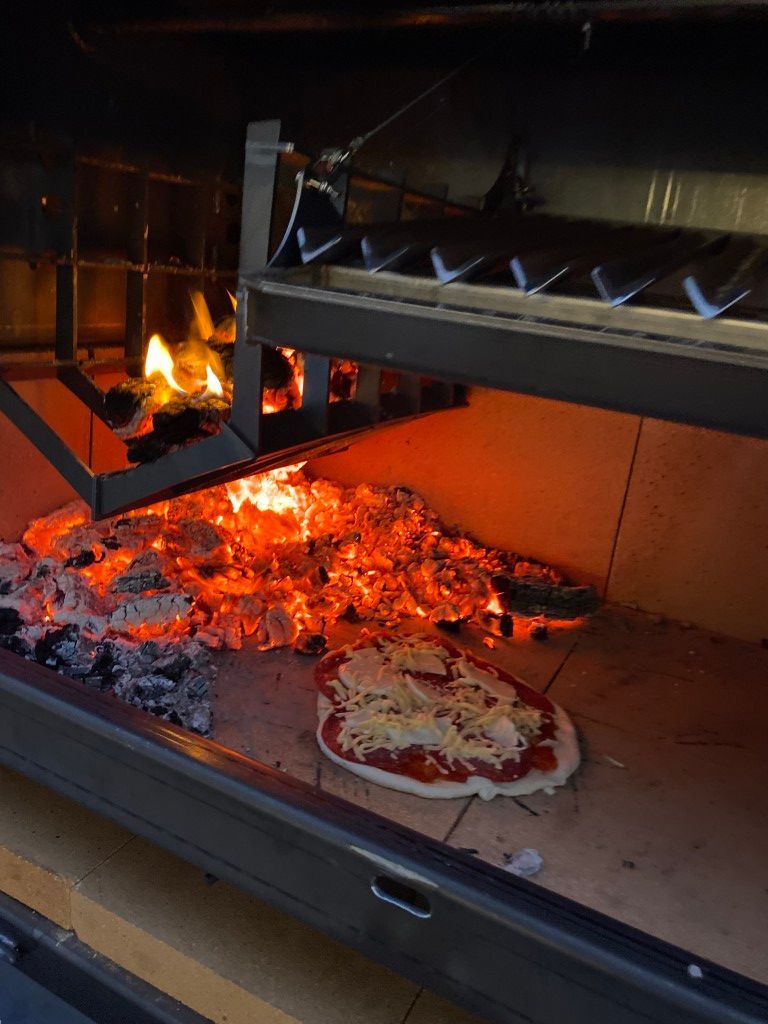A pizza is being cooked in a wood fired oven