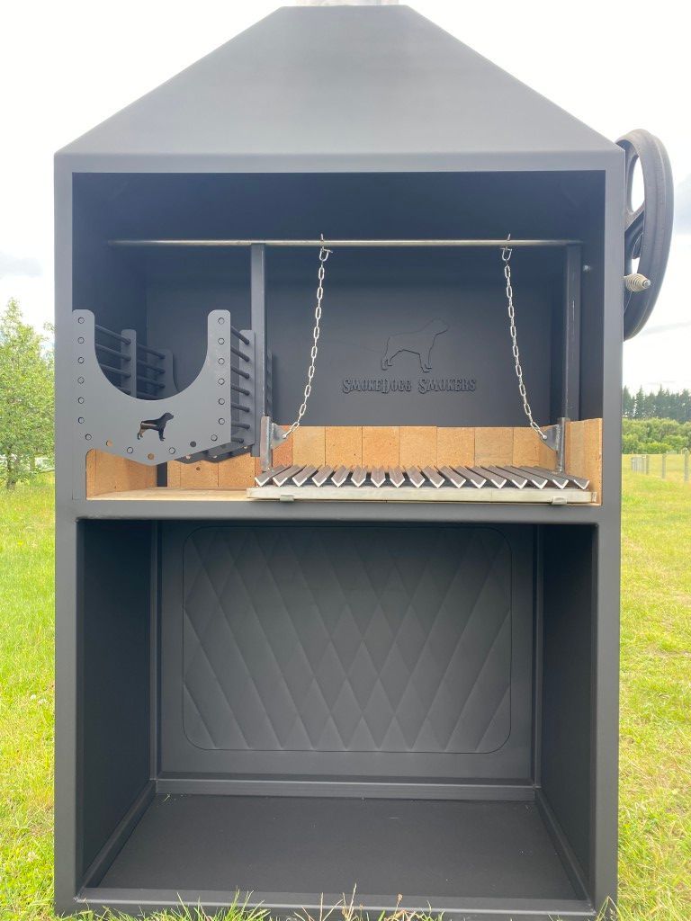 A large black grill is sitting in the middle of a grassy field.