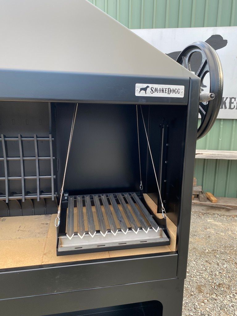 A black grill is sitting in front of a green building.
