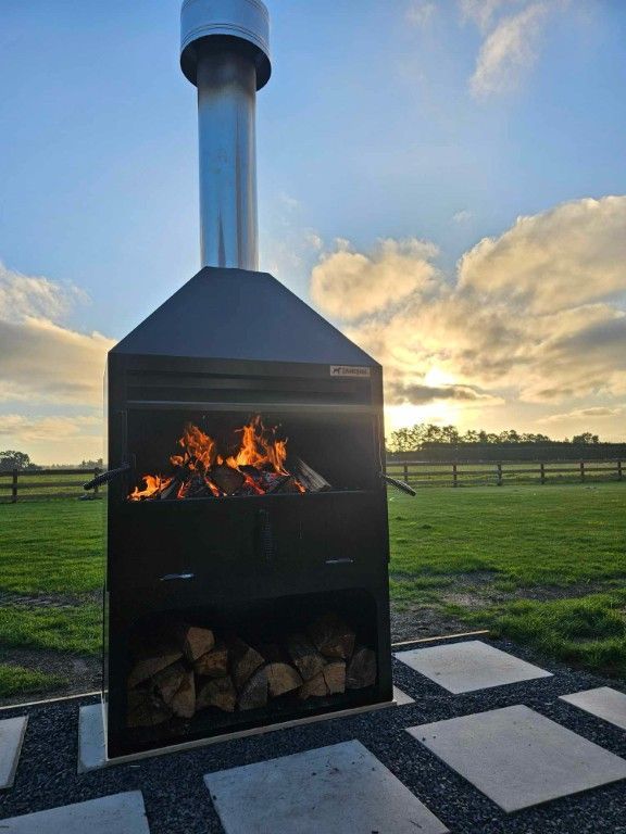 A large fireplace is sitting in the middle of a grassy field.