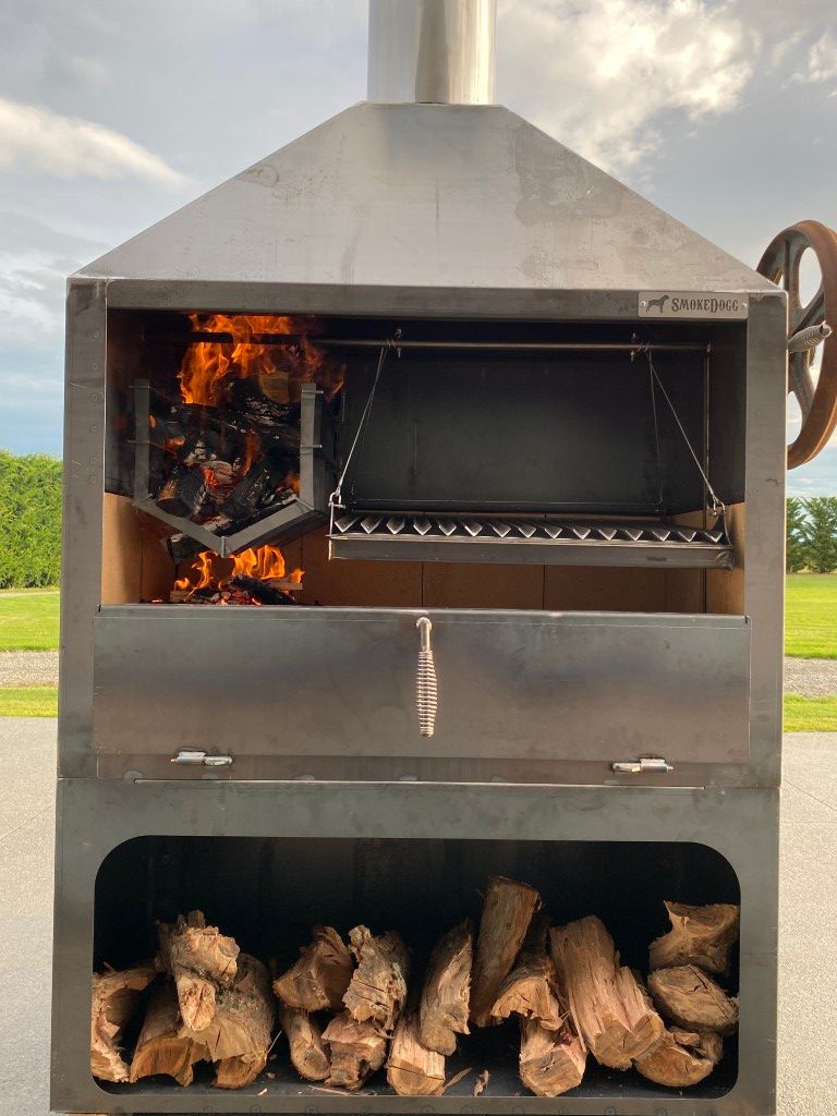 A large stainless steel grill with a lot of wood in it.