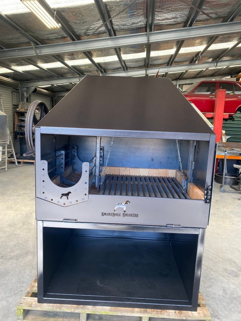 A large stainless steel grill is sitting on top of a wooden pallet in a warehouse.