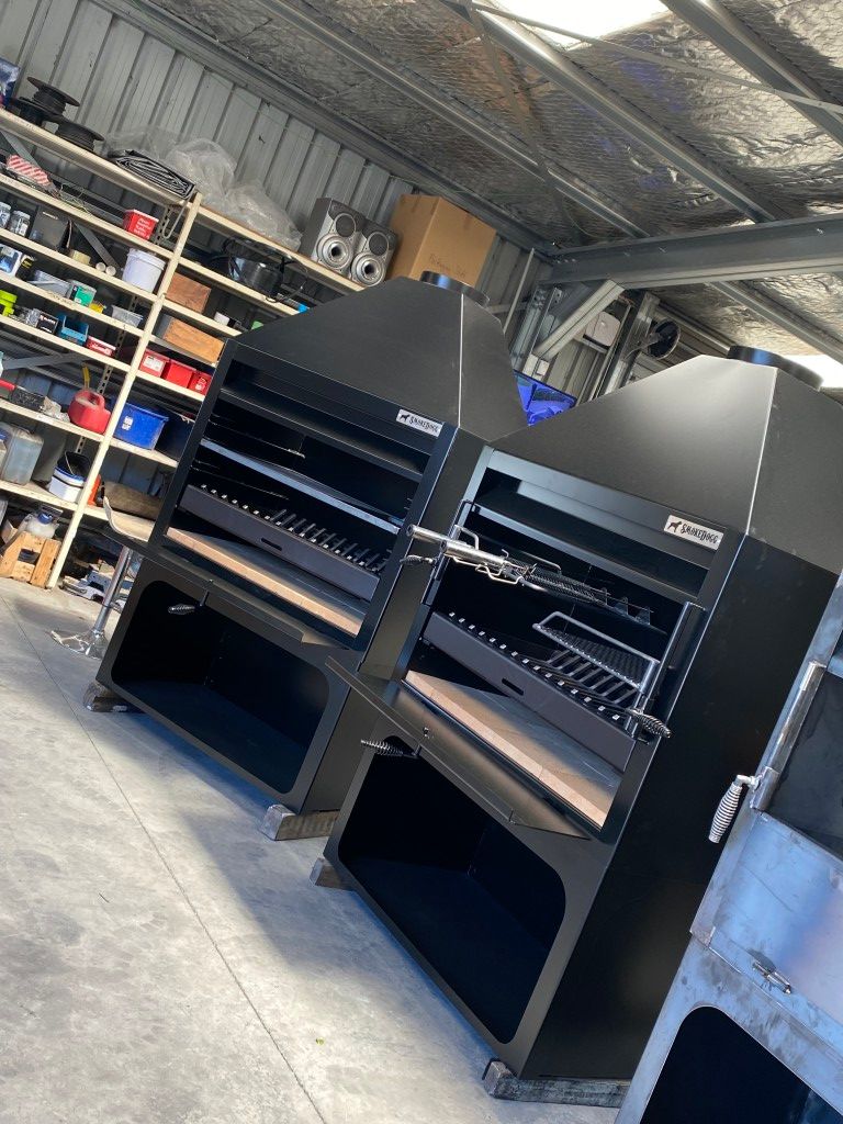 A row of black grills are sitting next to each other in a warehouse.