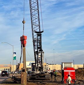 A large crane is lifting a pole on a construction site.