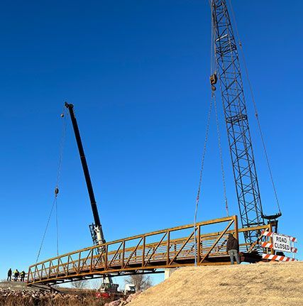 A crane is lifting a bridge over a body of water.