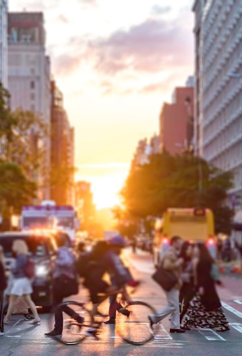 A blurry picture of people crossing a city street at sunset
