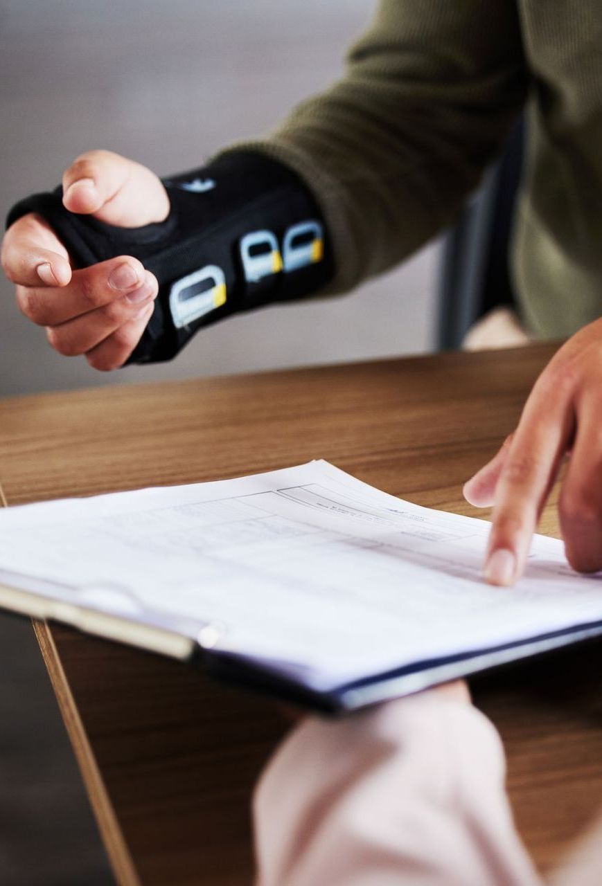 A person wearing a wrist brace is holding a piece of paper