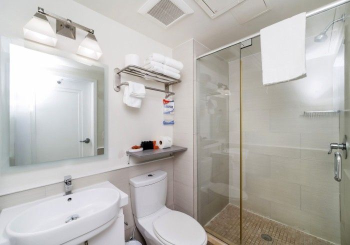 Bright modern bathroom with sink, toilet, mirror, shower, and glass shower door