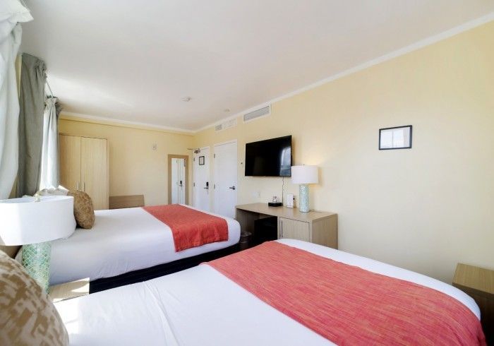 Hotel room with two double beds, red bedspreads, TV, and desk