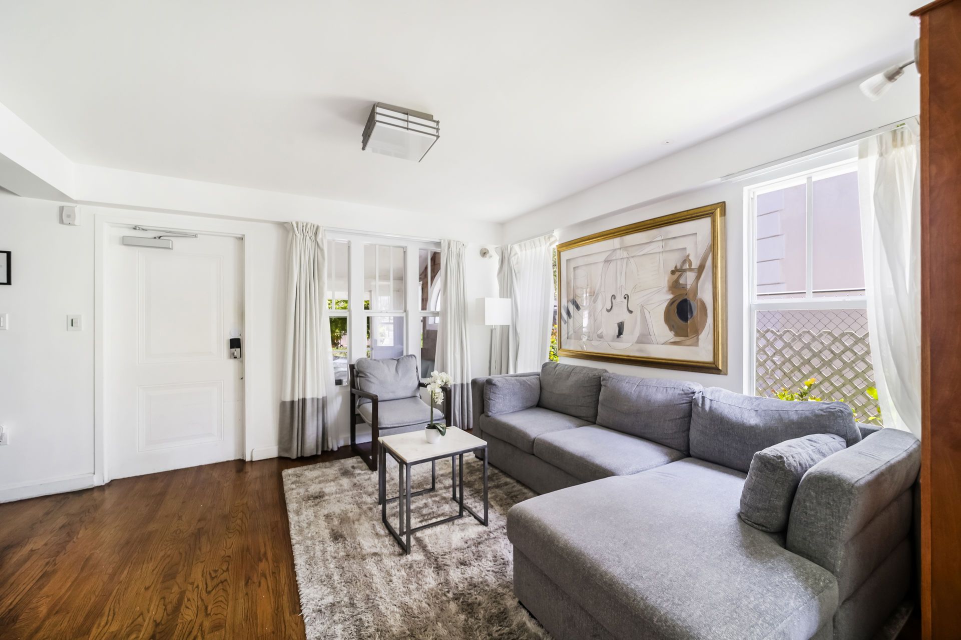 Bright living room with gray sectional sofa, coffee table, wall art, and hardwood floors