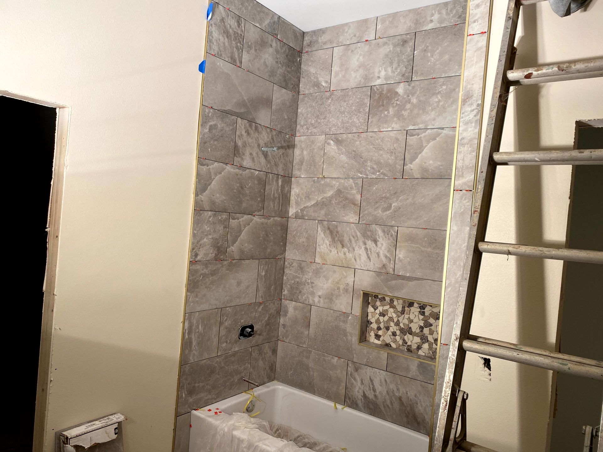 remodeler contractor working on a bathroom under construction with a bathtub and a ladder.