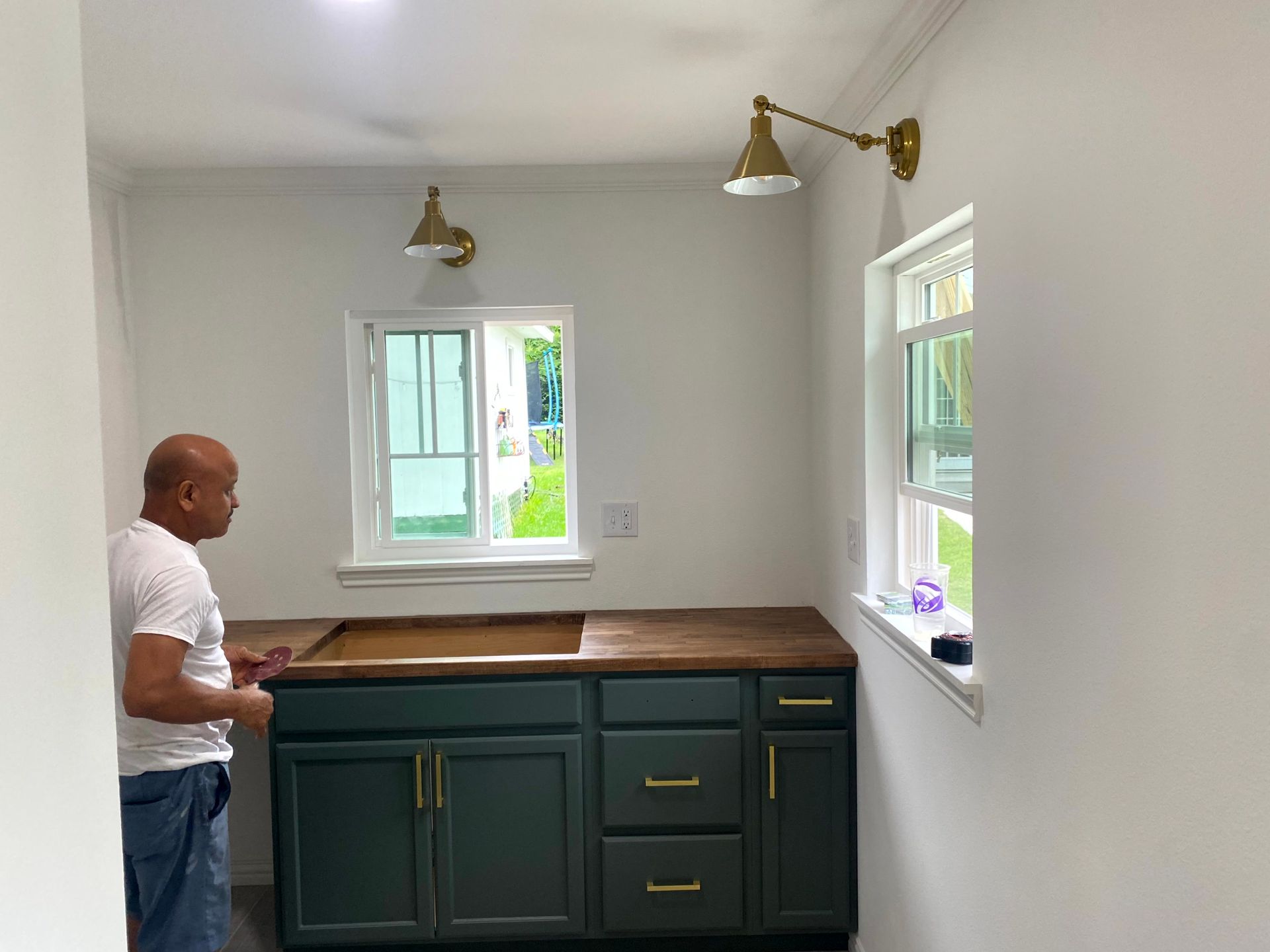 A remodeling contractors is standing in a kitchen with green cabinets and a window.