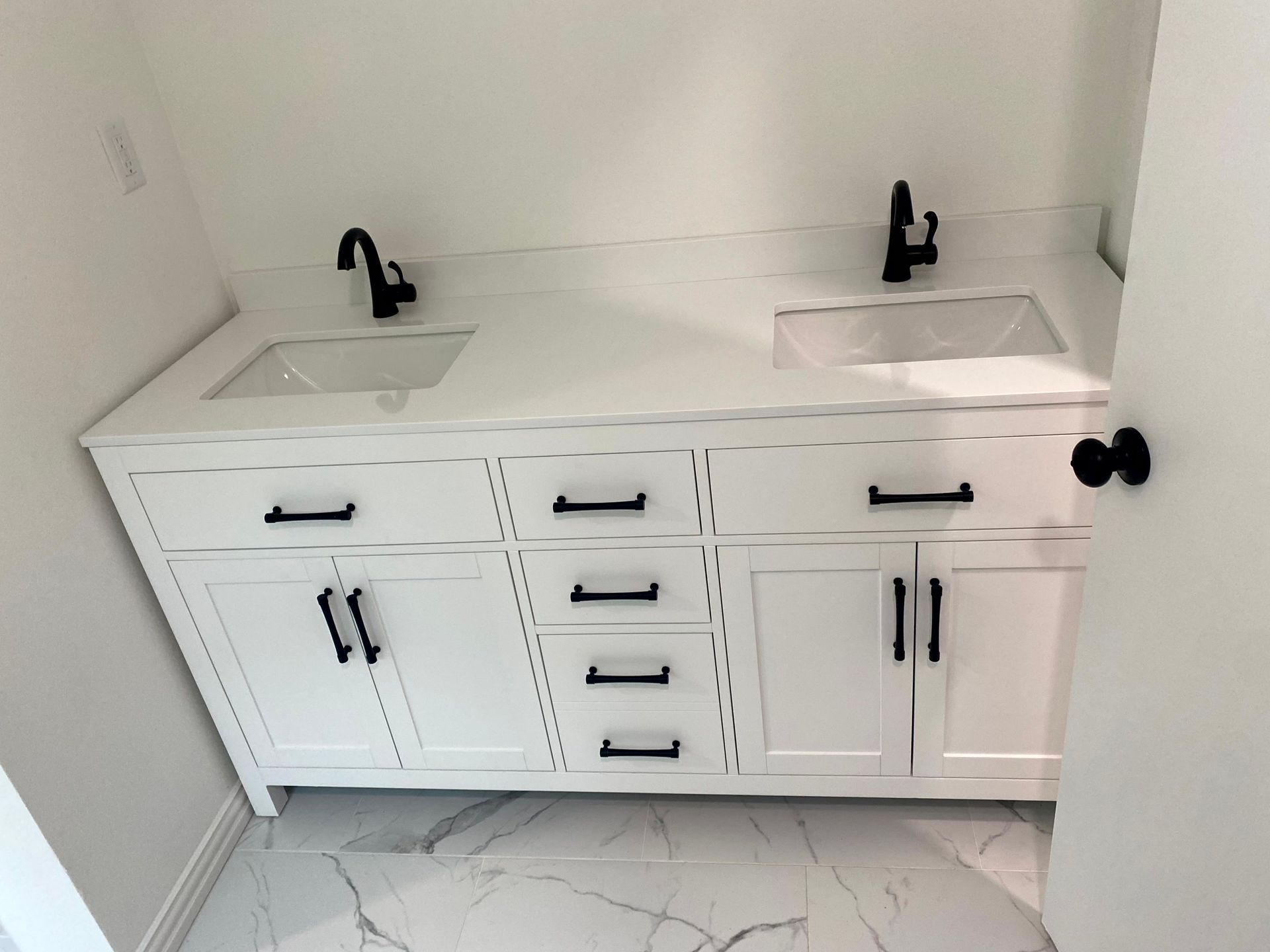 A bathroom with two sinks and white cabinets by remodeling contractors.