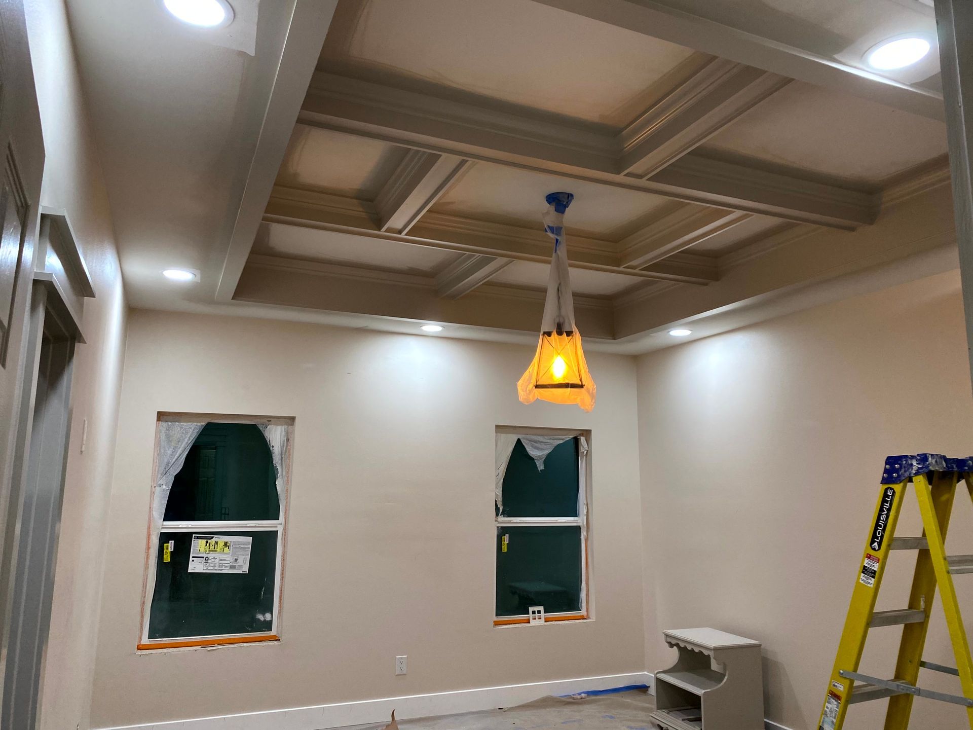 A room with a ladder and a light hanging from the ceiling with crown molding by home improvement contractors.