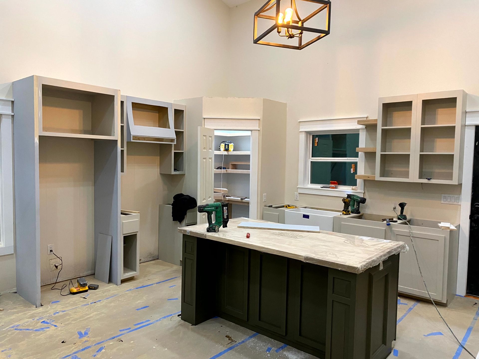 A kitchen under construction with a large island in the middle of the room by remodeler.