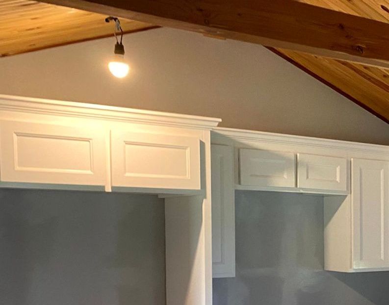 A kitchen with white cabinets and a light hanging from the ceiling by remodeling contractors.