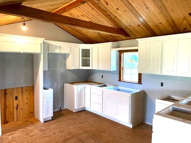 A kitchen with white cabinets and a wooden ceiling by home renovating contractors.