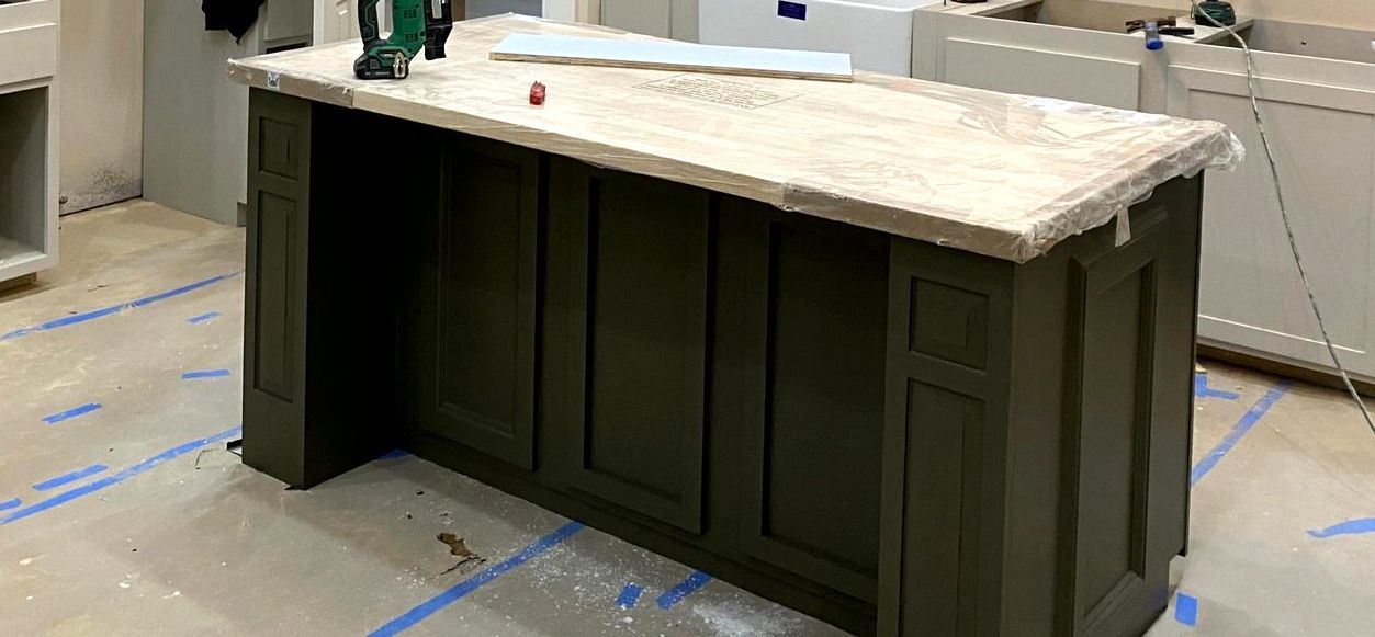 A kitchen island with a marble counter top is being built in a kitchen by remodeling contractors.