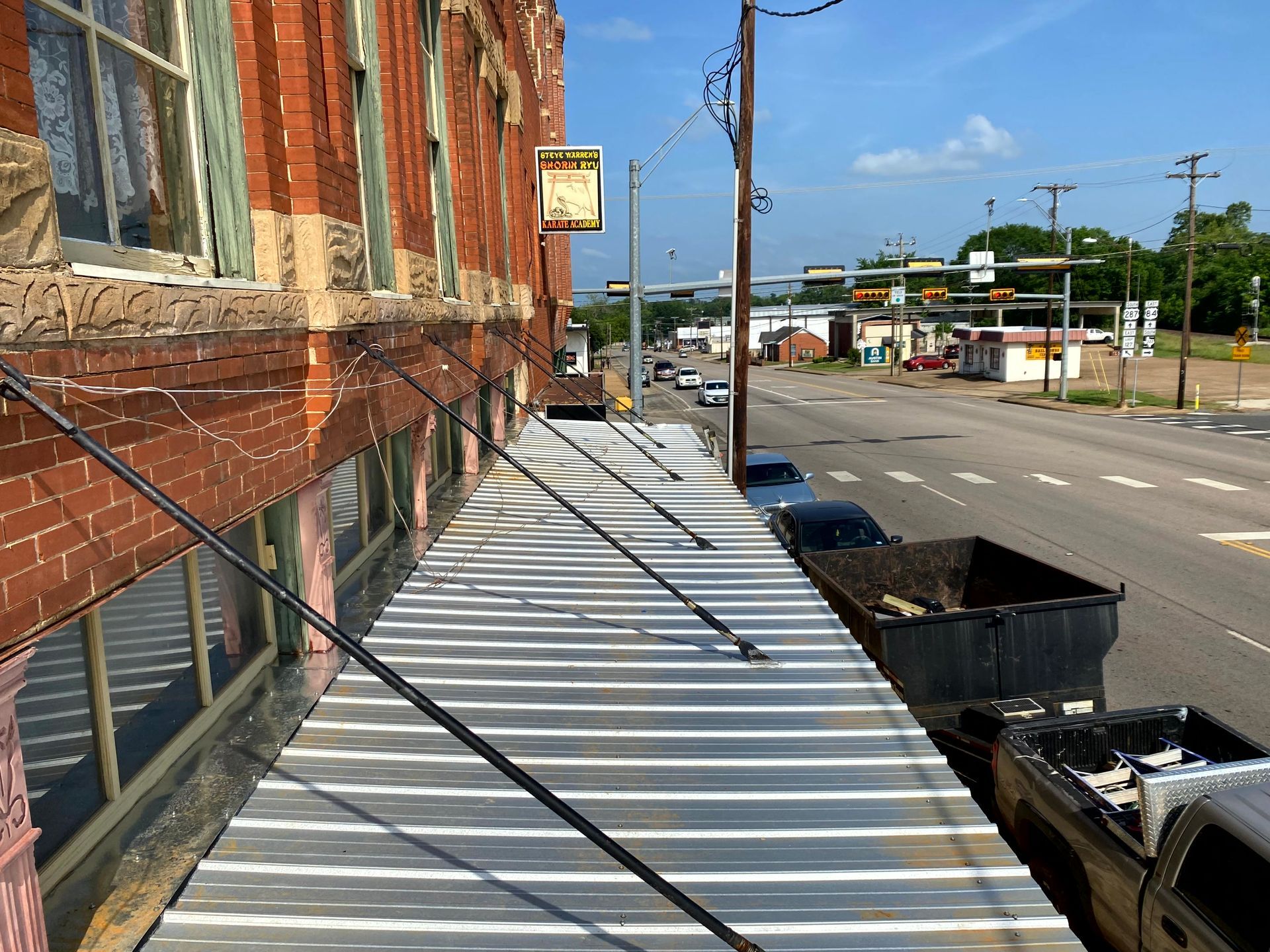A brick building with a metal awning on the side of it by by remodeling company.