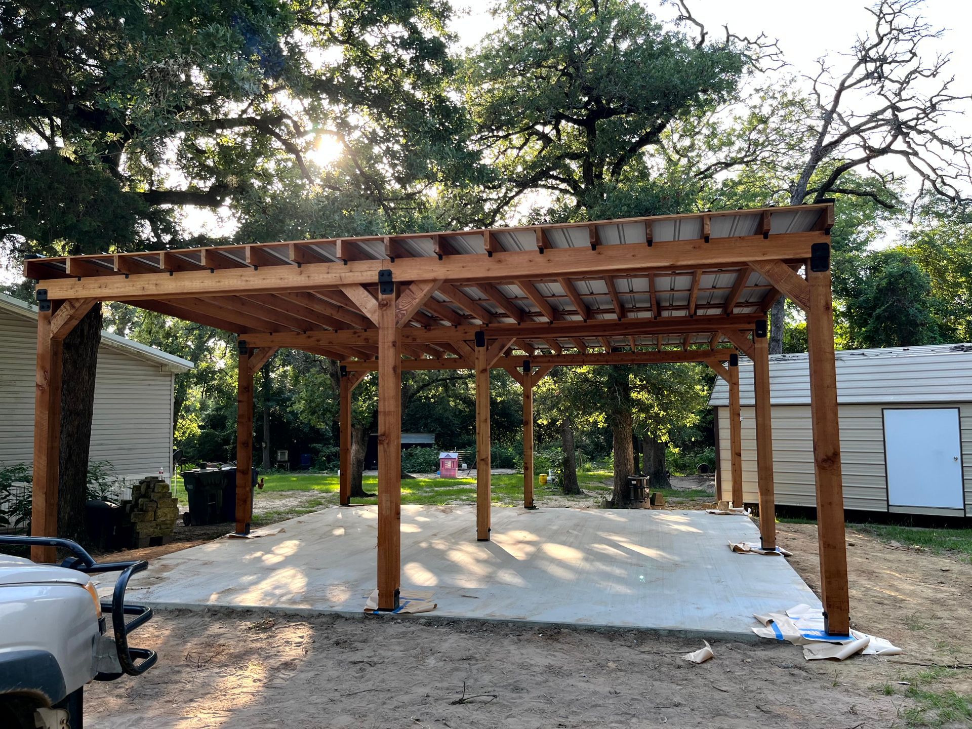 A carport is being built in the backyard of a house by by remodeling contractors.