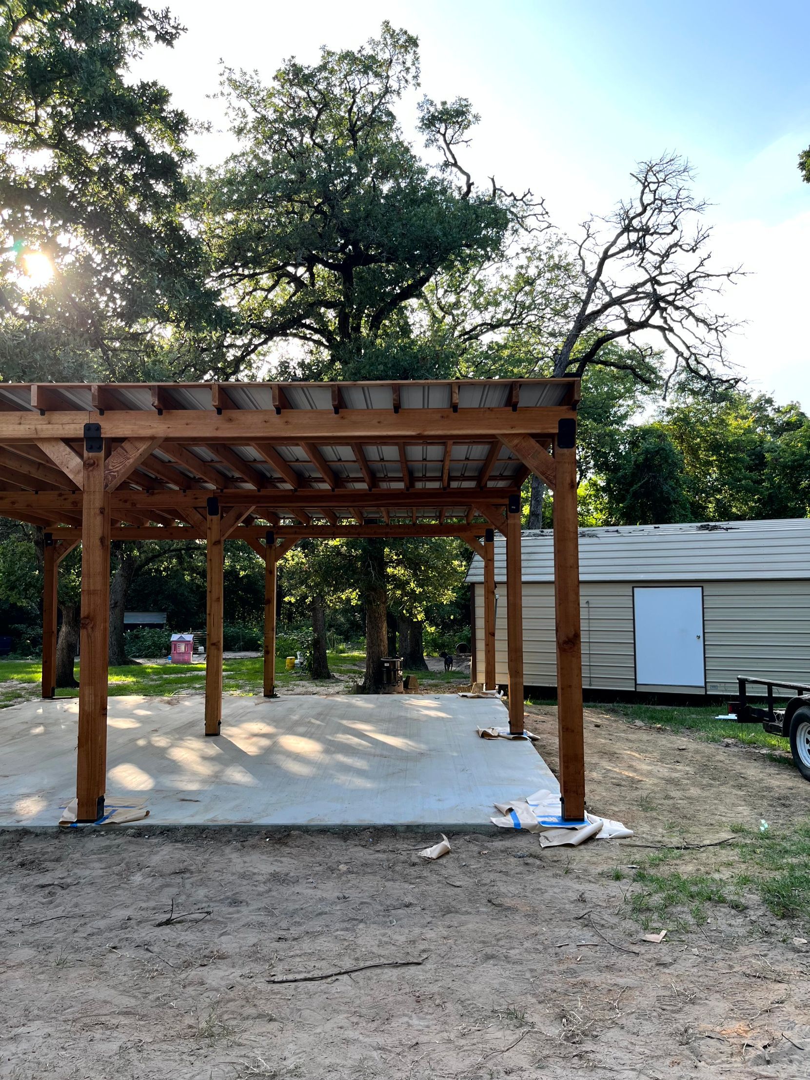 A wooden pergola is being built in the backyard of a house by by remodeling contractor company.
