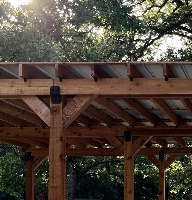 A wooden structure with a metal roof is surrounded by trees, a job completed by home renovating contractor.