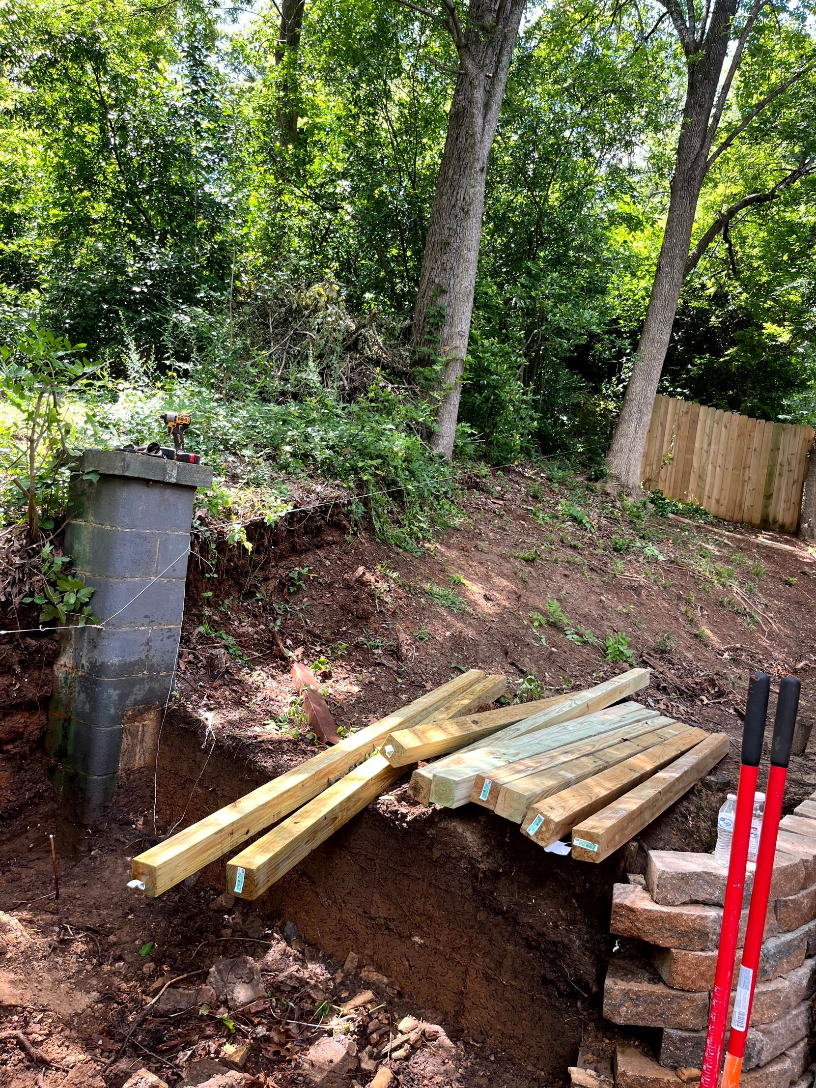 A pile of wood is sitting on top of a pile of bricks in the dirt prepping the job site by remodeling contractors.