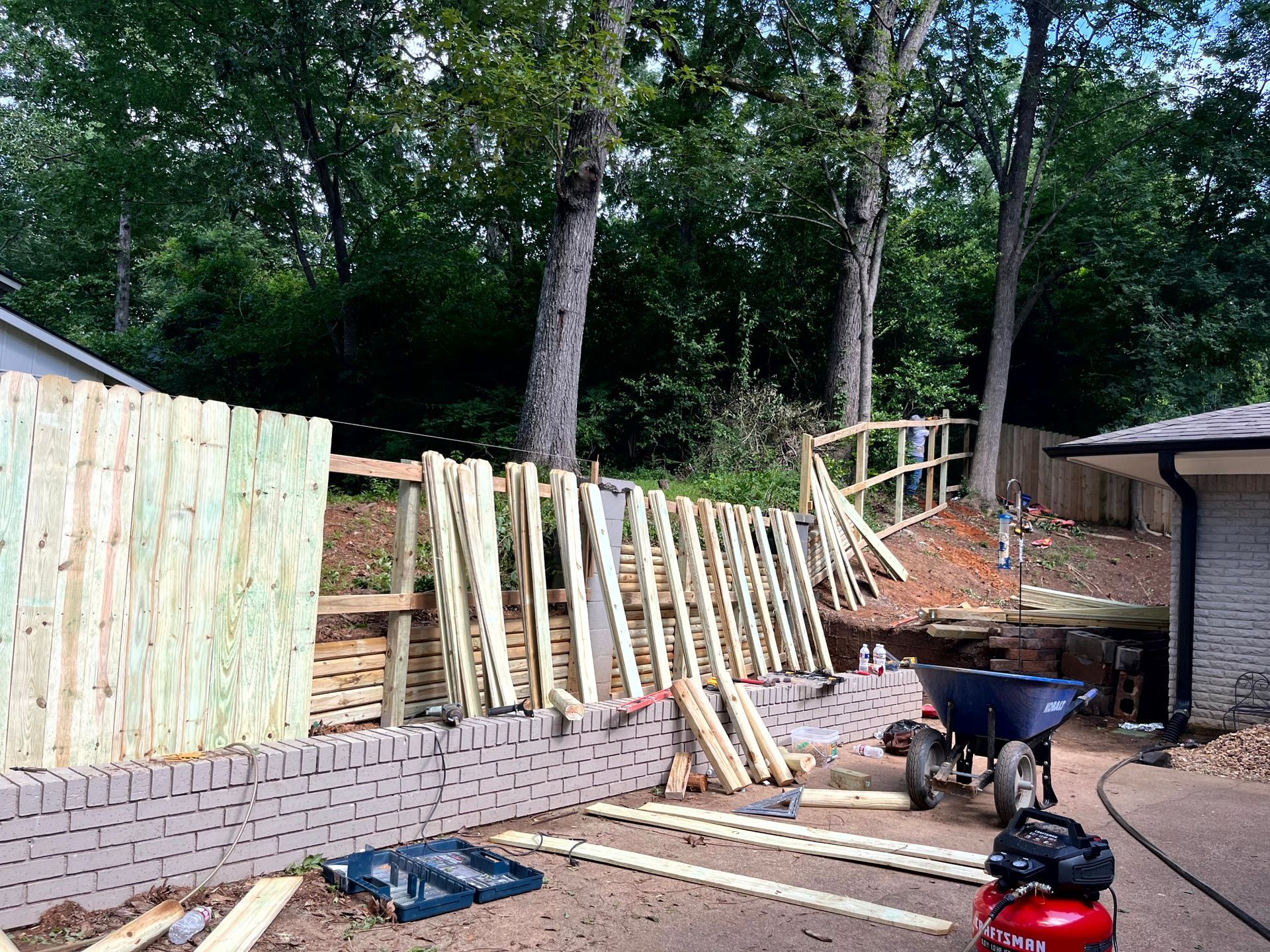 A wooden fence is being built in the backyard of a house by remodeling contractors.