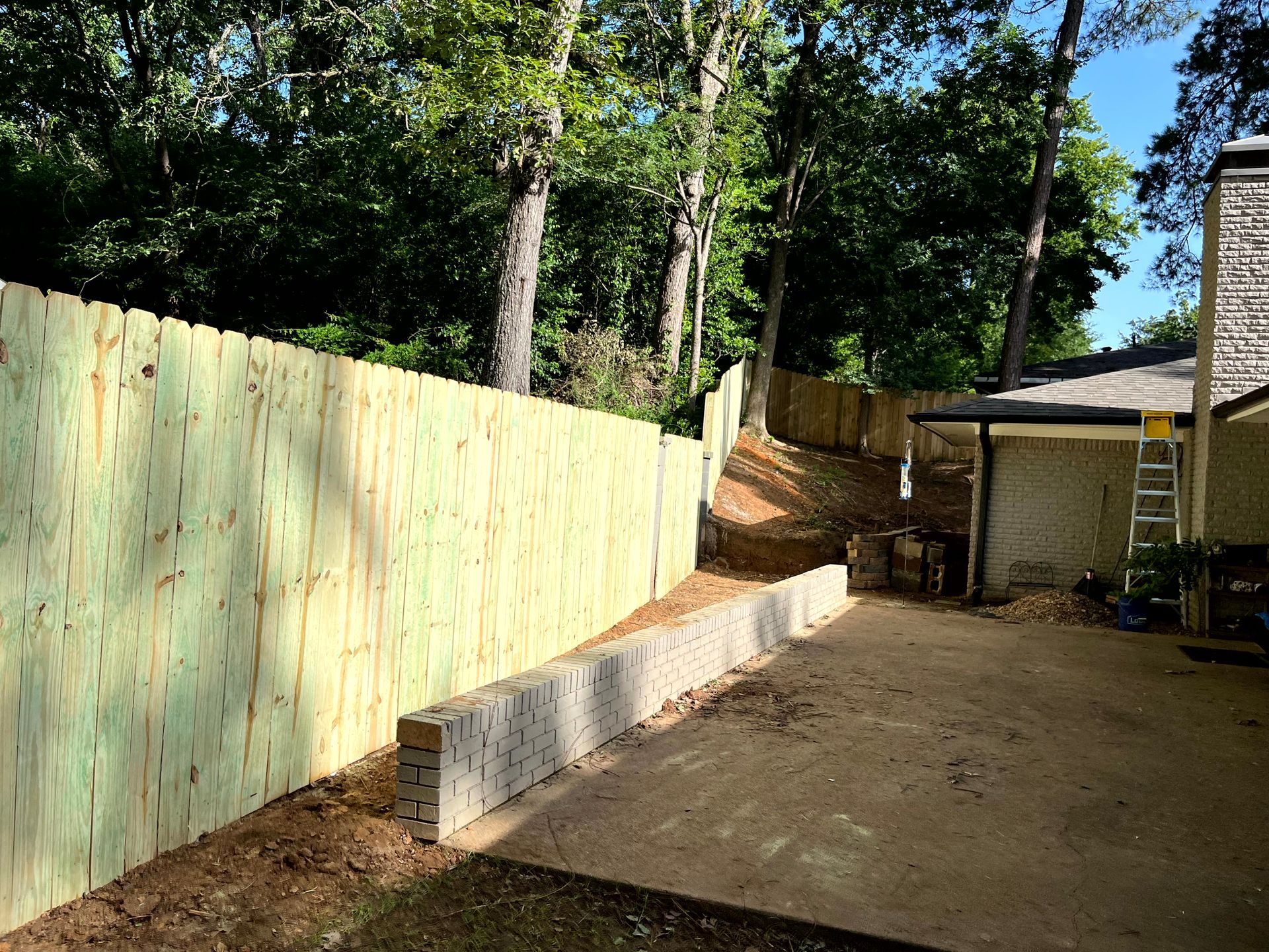 A wooden fence is being built in the backyard of a house by remodeling contractors.