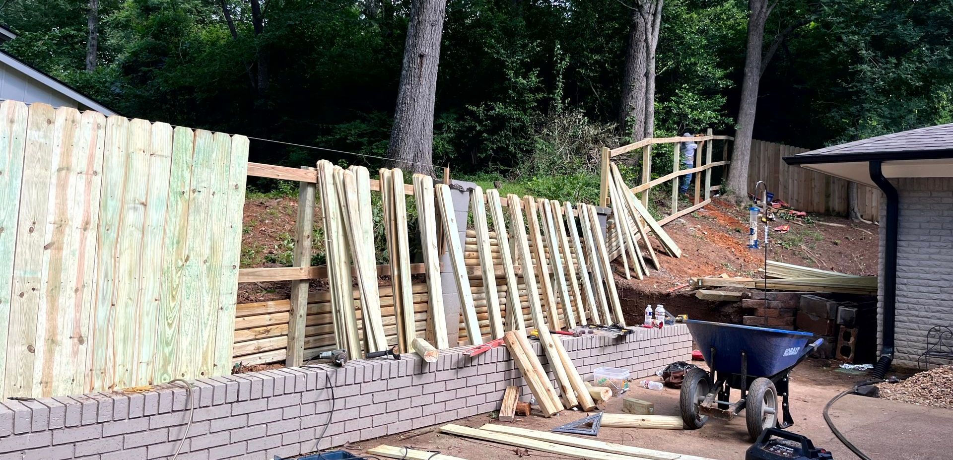 A wooden fence is being built next to a brick wall made by remodeling contractor.