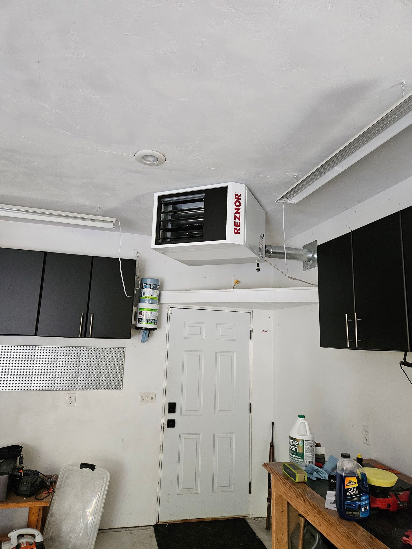 A garage with a heater hanging from the ceiling.
