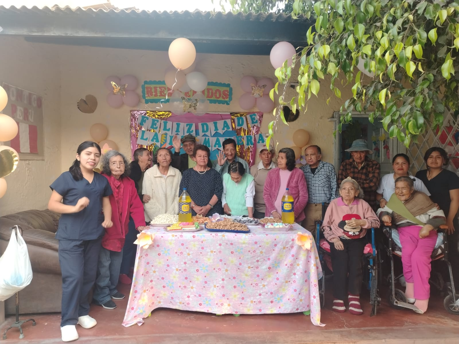 Un grupo de personas mayores celebra una fiesta con globos y una mesa decorada al aire libre.
